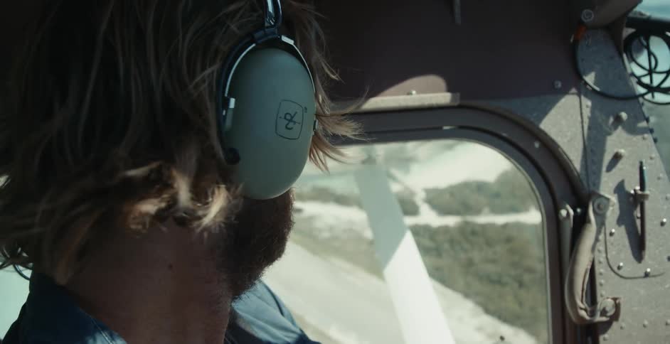A close up of a pilots face as he flies a plane looking out the window and then forward