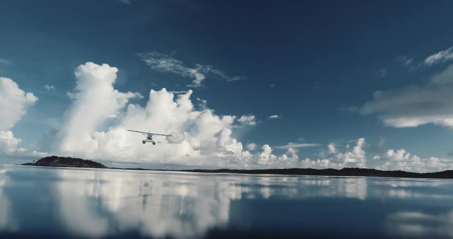 A plane is flying over a body of water at midday