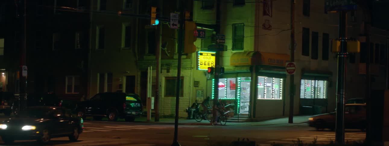 People ride their bikes past a corner store at night