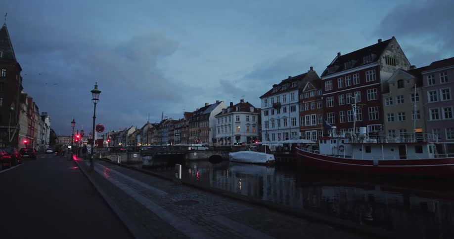 A view of a downtown european city street on the river waterfront at dusk with boats and architecture