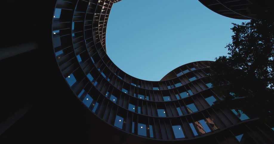 A straight up view of an oddly shaped building with a clear blue sky
