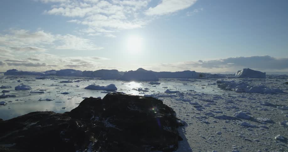 Aerial view of the sun setting over the mountains next to the arctic ocean