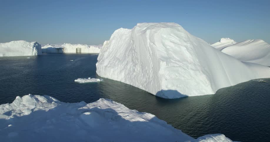 An aerial of large ice caps in the arctic ocean with shadows casted on the ice