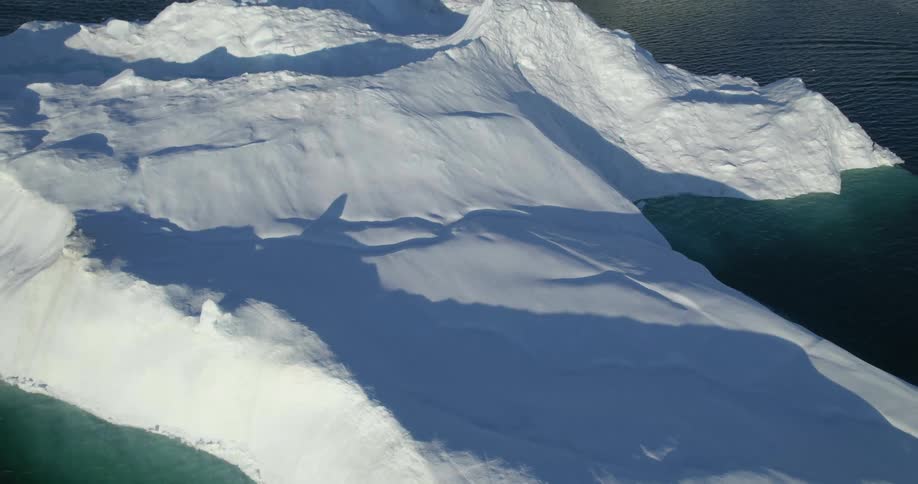 An aerial of large glaciers in the arctic ocean and a landscape of ice caps