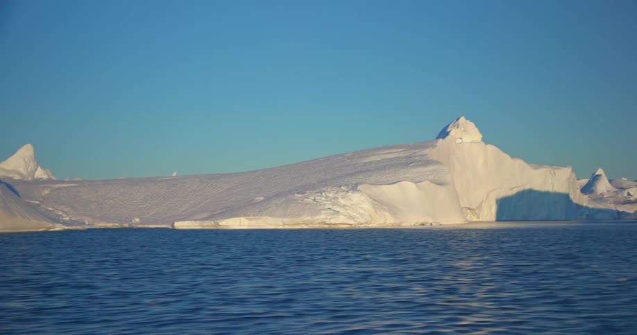 Traveling on ocean water past glacial landscape during the day