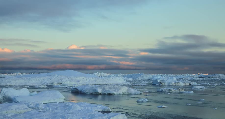 Boat moves among sea ice leaving a wake as sun rises