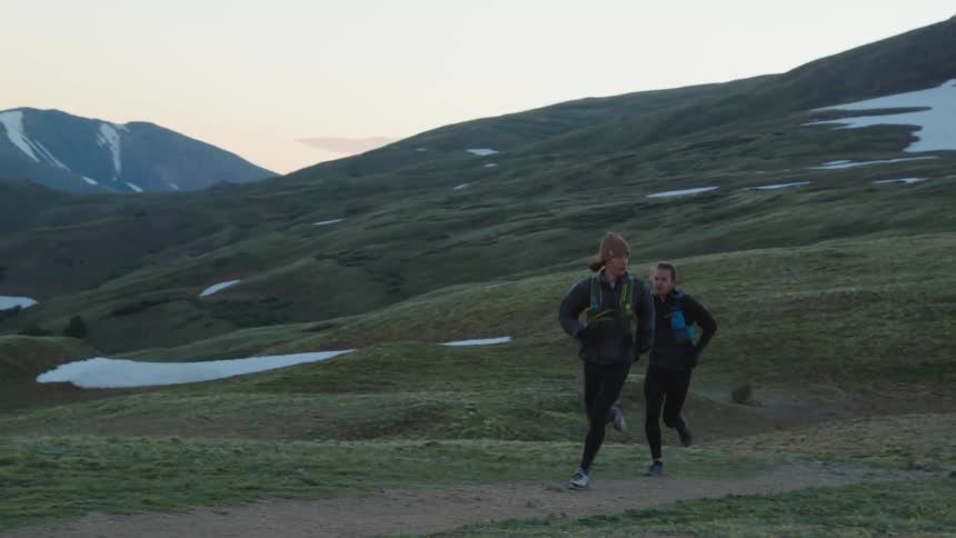 Two men are jogging in the wilderness at dusk