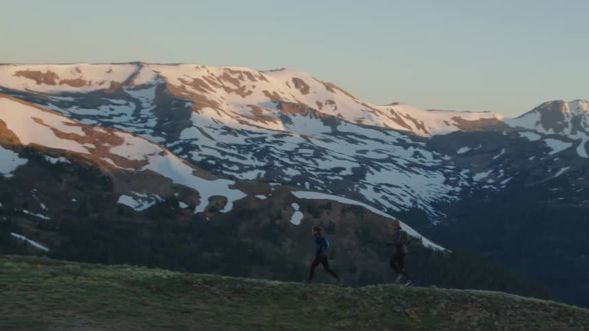 Two men are jogging along the mountain side at dusk
