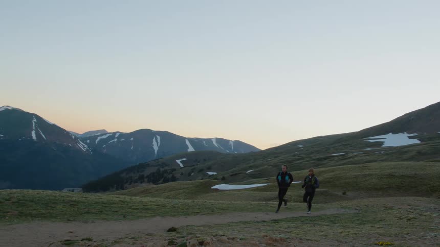 Two men running on a trail through the mountains with mountains landscapes and backgrounds