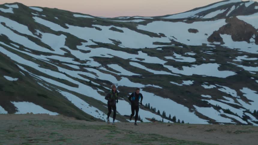 Two people are jogging in the wilderness at dusk