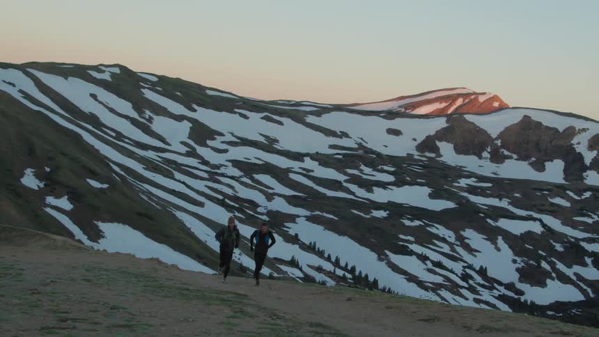 Two men are jogging outdoors while the sun is setting