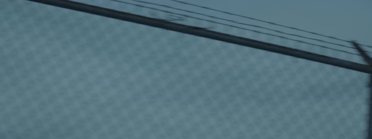 A barbed wire topped fence on a clear day