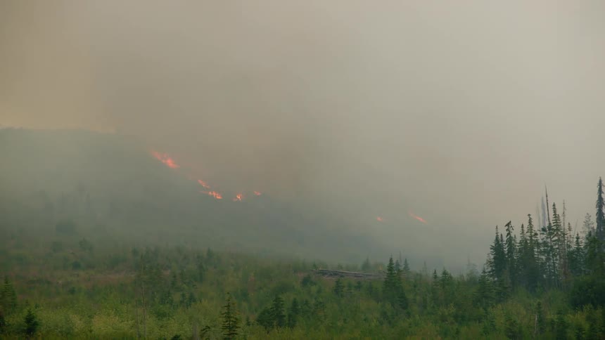 Panoramic view of a wildfire burning the forest on the slopes of a mountain at daytime