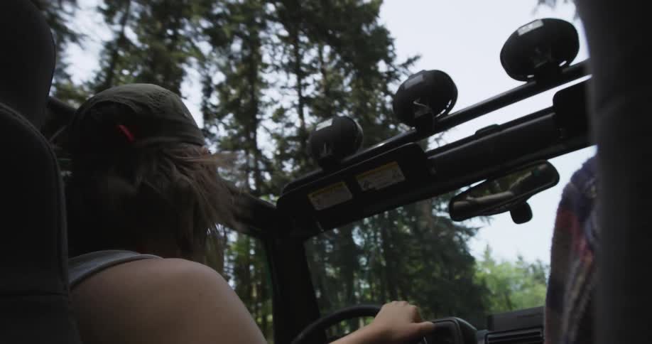 A man drives a jeep through a wooded area