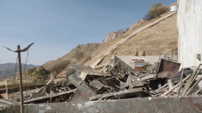 A scrapheap rests in front of a hill with a gutter