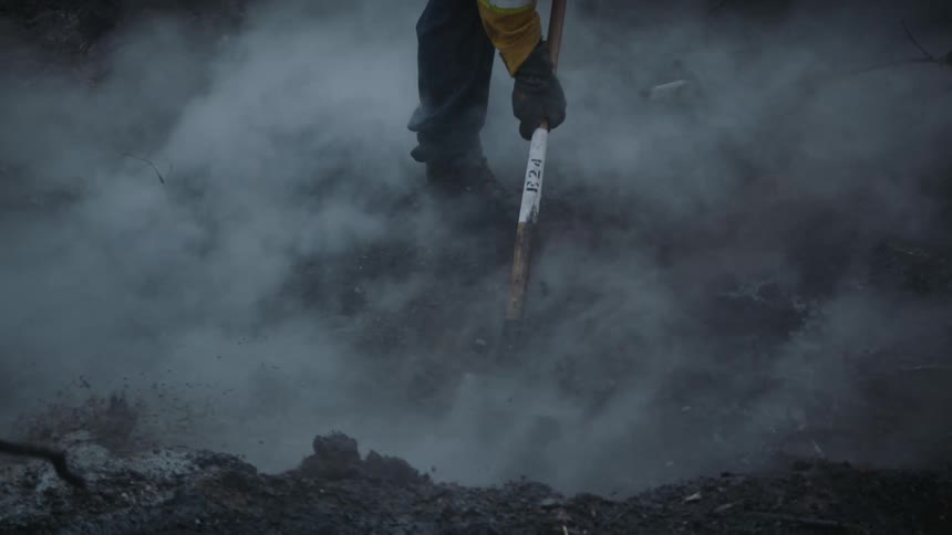 A firefighter is smothering flames with soil