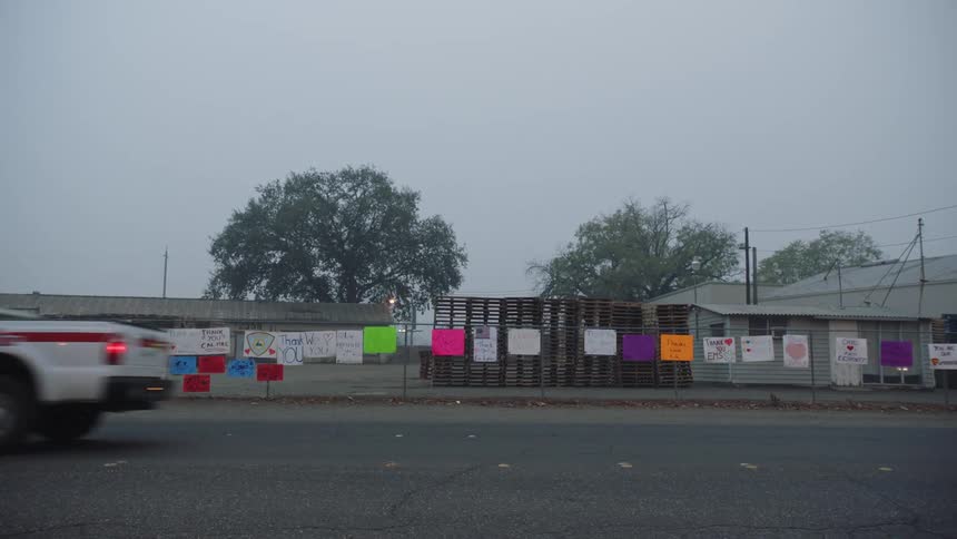 Signs on a fence as a emergency truck drives by