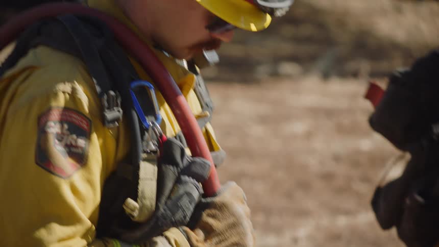 A firefighter sprays water from a hose in a field