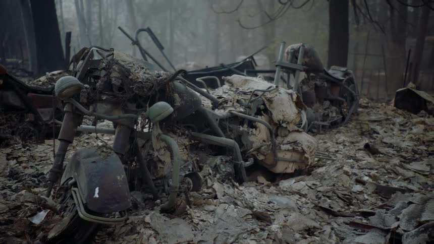 A burned motorcycle on top of a pile of rubble in the forest the aftermath of a fire