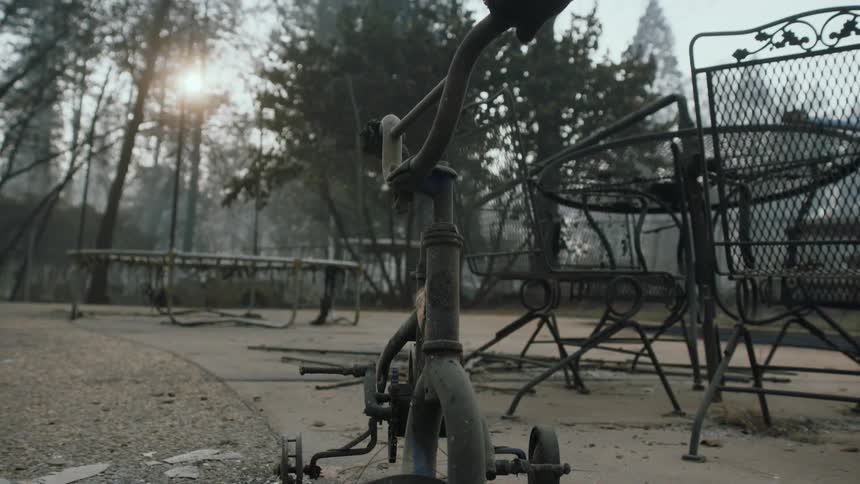 A closeup view of a burned tricycle on a concrete patio after a fire