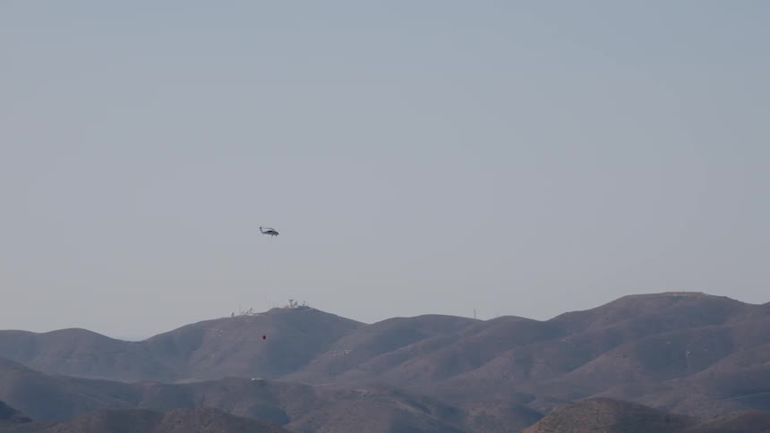A helicopter is flying over a hill landscape