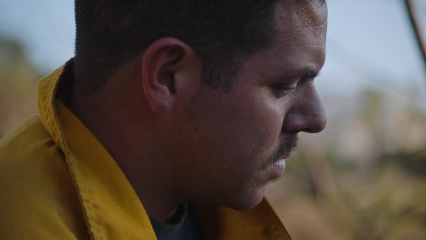 Close up of the face of a tired firefighter looking down while standing outdoors
