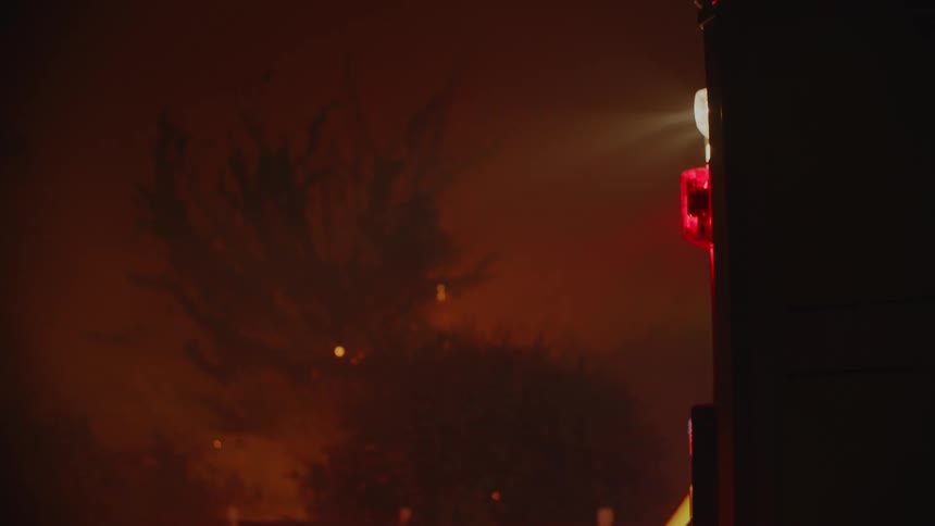 The fire truck is parked near the forest fire