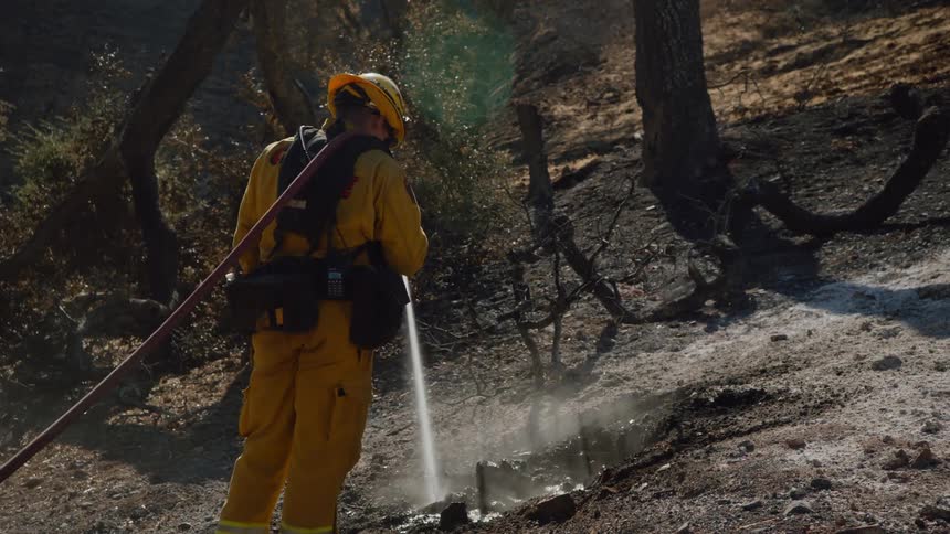 A firefighter is spraying water on a fire