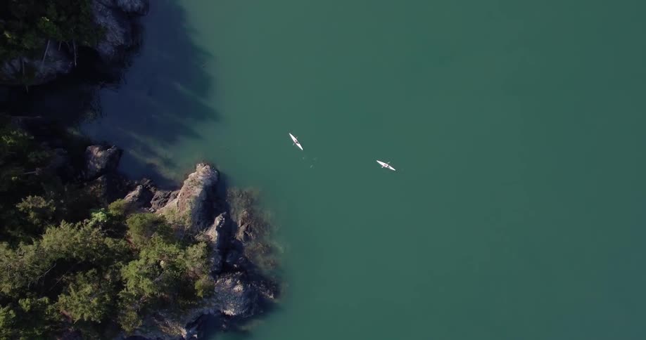 Canoes are traveling near the rocky shore below