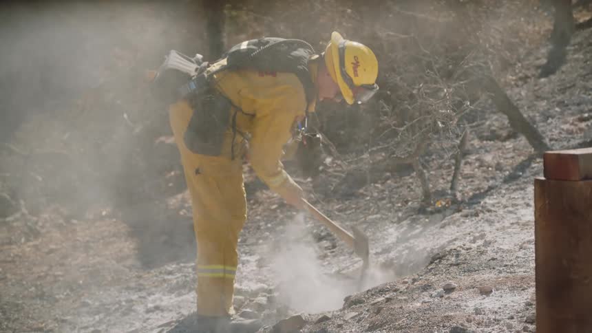 Firefighter digs at smoking ground on slope