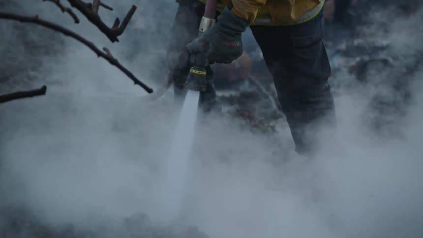 Two firefighter work among the smoke using hoses