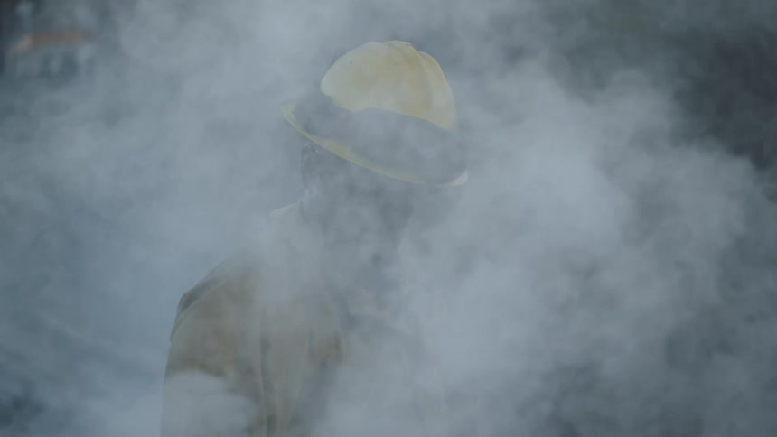 A fireman is standing in a thick cloud of smoke as it floats away