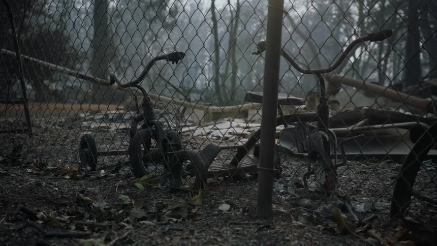 Close up of burnt tricycles near a wired fence in the forest at daytime