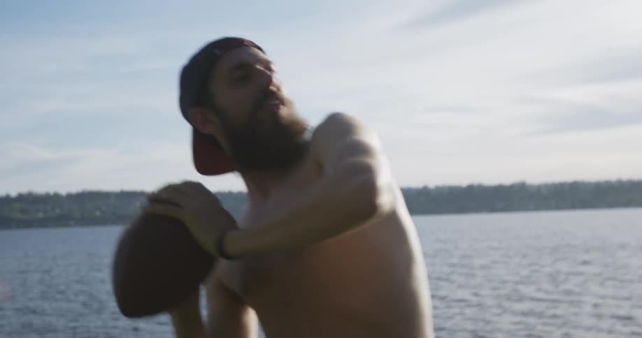 A man by a lake throws a football to a group of friends