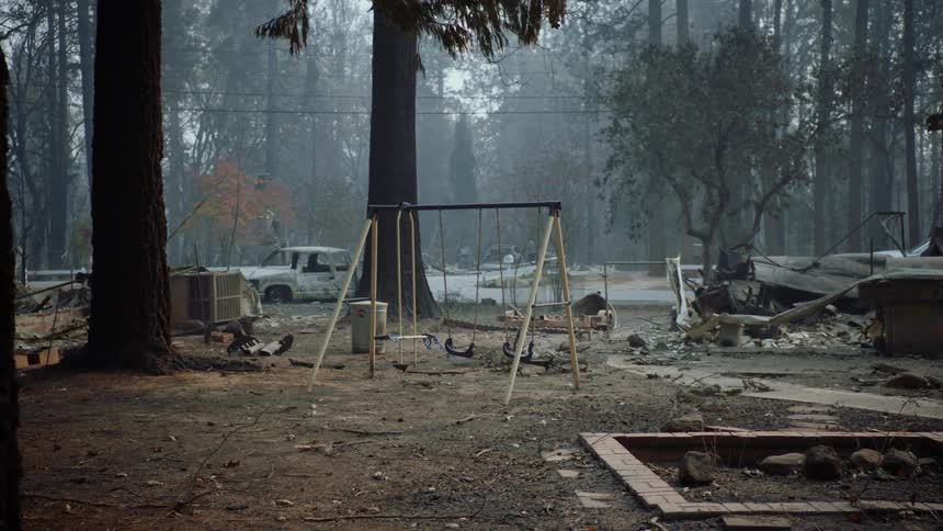 A swing set in a yard full of debris and rubbles and burnt cars