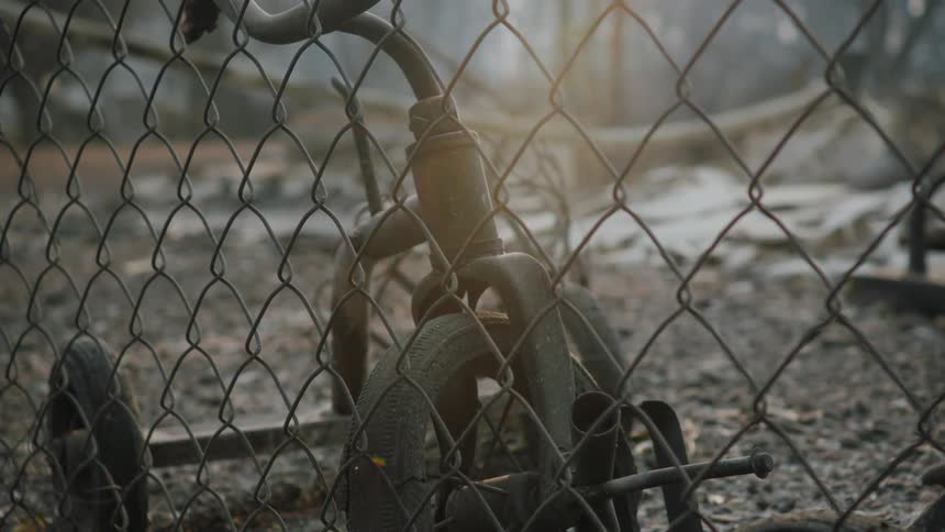 A closeup view of a burned tricycle behind a fence after a natural disaster
