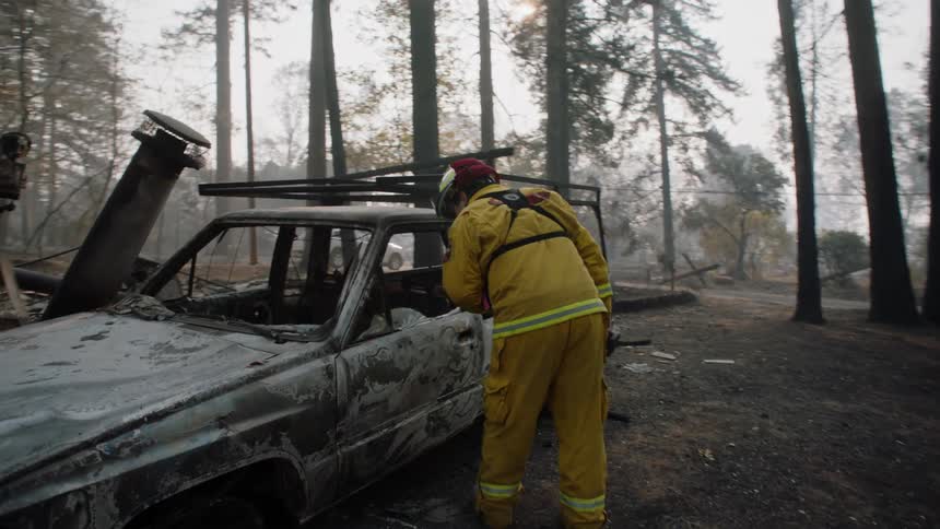 A firefighter examines a building and vehicle after a fire