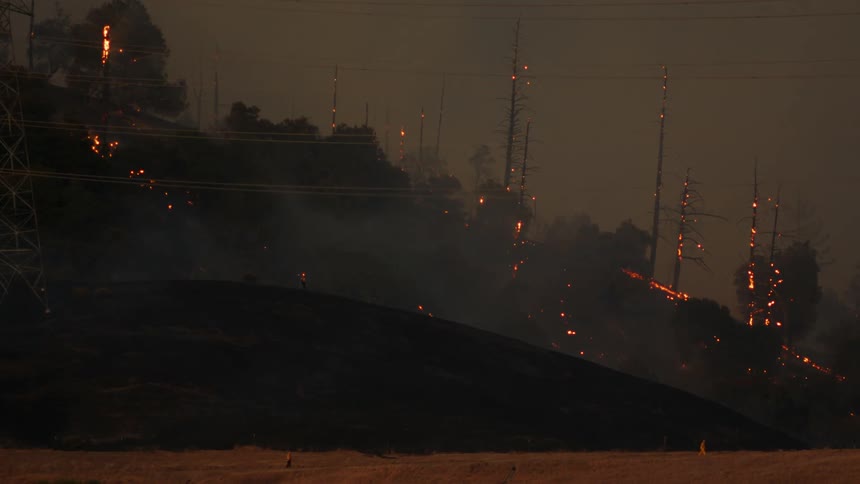 Silhouette of the smoldering remain of burning trees on the slopes of a mountain at night