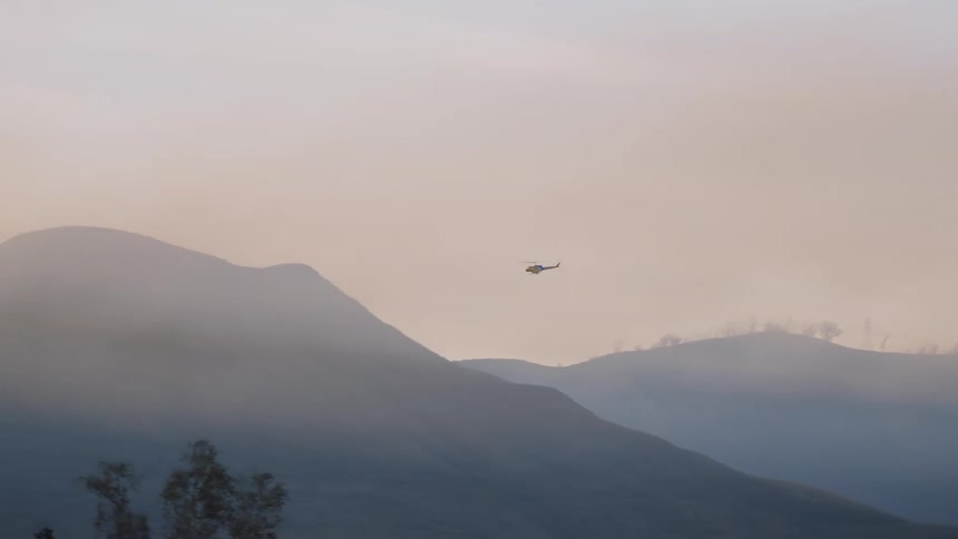 Helicopter flies over the mountains covered in mist at morning