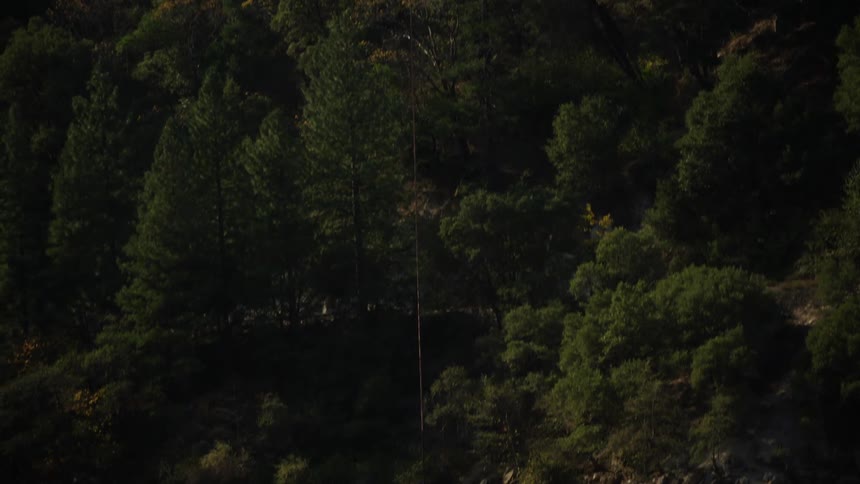 A helicopter lifts a helibucket out of a large reservoir after refilling it with water