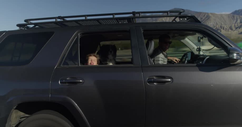 A child in the backseat of an suv opens the window and sings
