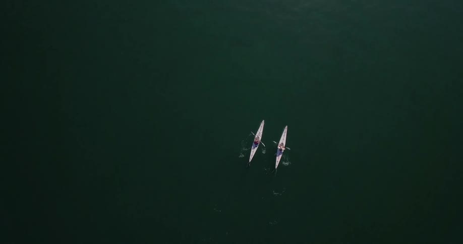 Two canoes are rowing below in the water