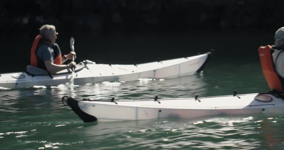 Two men paddle kayaks upstream