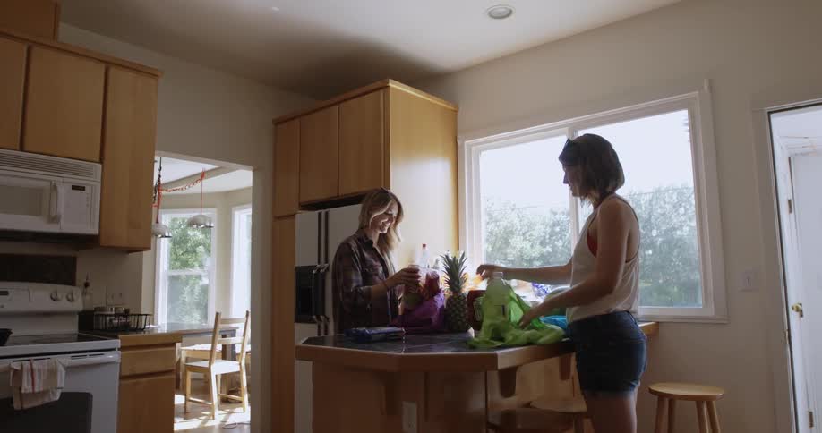 Two women unload groceries in the kitchen
