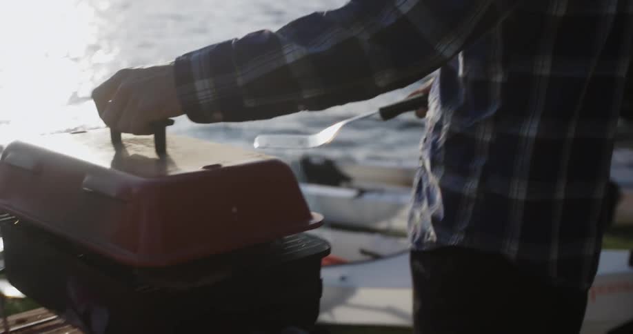 A man is cooking near a lake