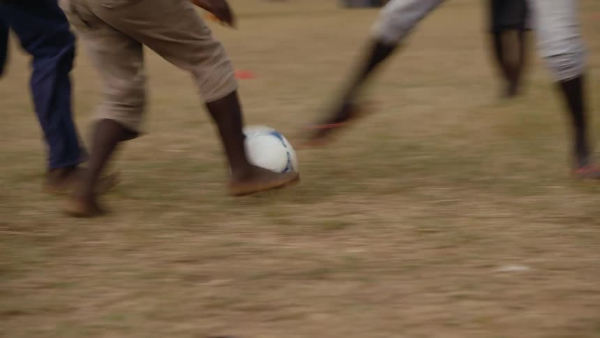 Group of barefoot people playing or practicing soccer on a field at daytime