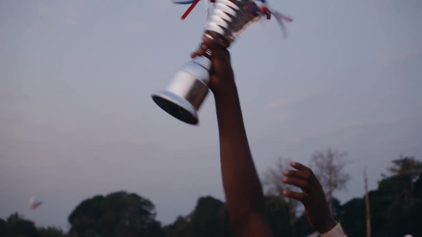 A persons hand with a trophy in it as they raise it up in excitement