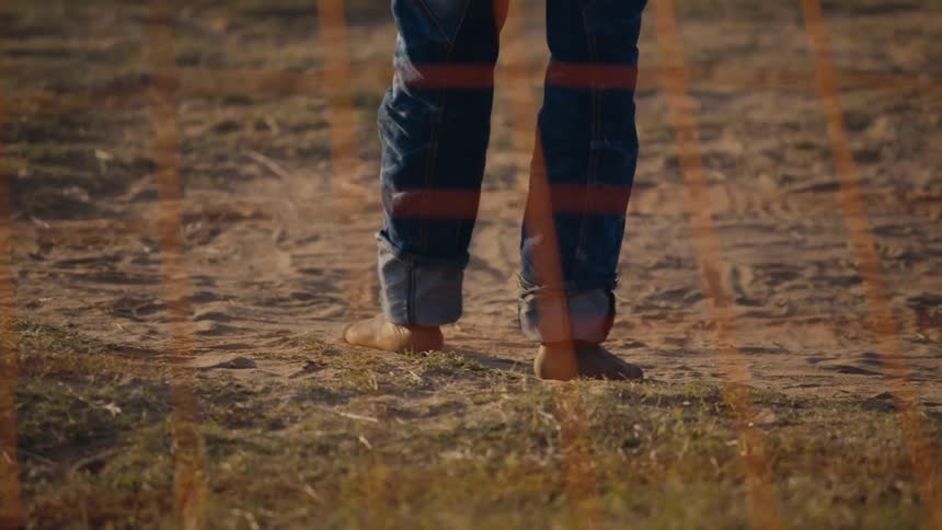 A persons feet as they back up in sand toward an orange net