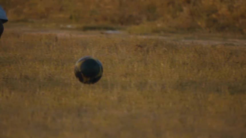 Youths play soccer in field near trail