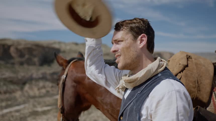 Dusty cowboy wipes sweat from his forehead